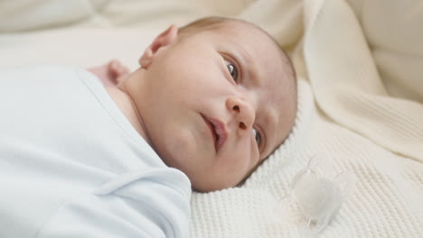 Close-Up-Of-A-Cute-Newborn-Baby-Lying-On-Bed-And-Moving-1