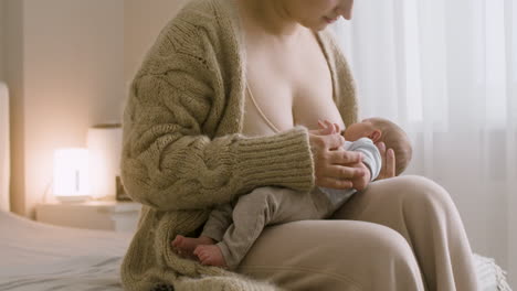 Loving-Young-Mother-Breastfeeding-Her-Newborn-Baby-While-Sitting-On-The-Bed-At-Home-2