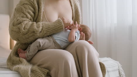 Loving-Young-Mother-Breastfeeding-Her-Newborn-Baby-While-Sitting-On-The-Bed-At-Home-3