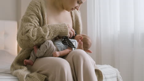 Loving-Young-Mother-Breastfeeding-Her-Newborn-Baby-While-Sitting-On-The-Bed-At-Home-4