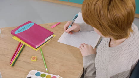 Niño-Pelirrojo-Escribiendo-En-Un-Cuaderno-Una-Oración-Pasada-Simple-Durante-La-Clase-De-Inglés-En-La-Escuela