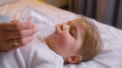 Close-Up-View-Of-A-Baby-Moving-His-Arms-And-Legs-While-His-Mother-Giving-Him-Water-From-Feeding-Bottle
