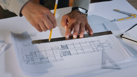 Top-View-Of-Architect-Hands-Drawing-A-Building-Plan-On-The-Big-Sheet-Of-Paper-On-The-Desk