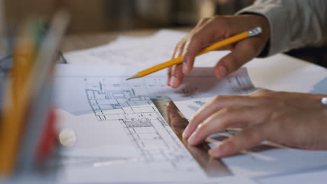 Close-Up-View-Of-Architect-Hands-Drawing-On-The-Plan-With-A-Pencil-And-Rule-On-The-Desk
