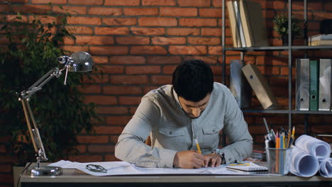 Hombre-De-Negocios-árabe-Que-Trabaja-Como-Diseñador-O-Arquitecto-Mientras-Dibuja-Algo-Con-Un-Lápiz-Y-Regla-Sobre-La-Mesa-En-Su-Oficina