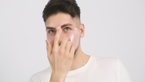 Young-Man-Applying-Lotion-To-His-Face