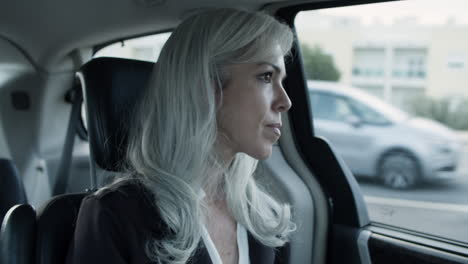 Gray-Haired-Woman-Wearing-Suit-And-Sitting-In-Moving-Car