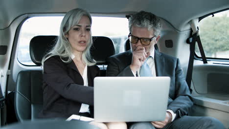 Business-Partners-Working-Together-Using-Laptop-In-Car