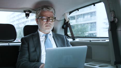 Fokussierter-Senior-Geschäftsmann-Mit-Laptop-Im-Auto