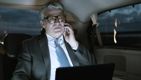 Man-In-Suit-Talking-On-Mobile-Phone-And-Using-Laptop-In-Car
