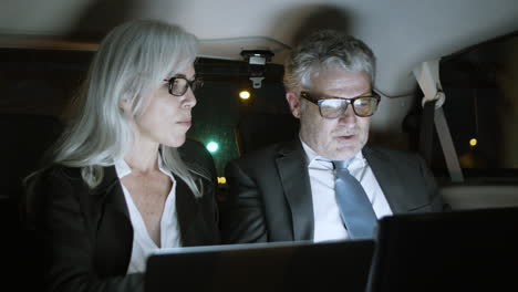 Business-Partners-Using-Laptops-In-Car-At-Night