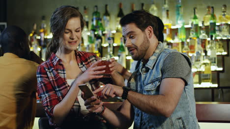 Couple-Standing-In-The-Bar-At-Night-With-Their-Drinks