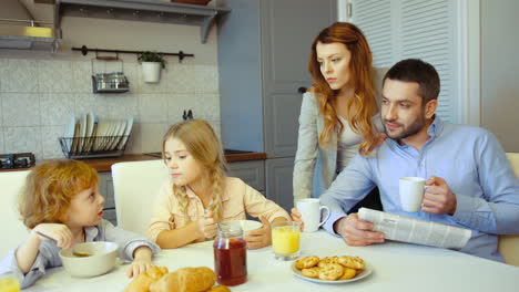 A-Mother-Having-Coffee-In-The-Kitchen-While-Her-Husband-Talks-To-Their-Kids