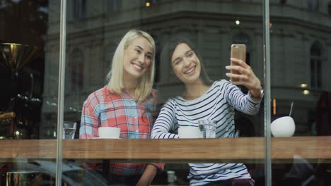Zwei-Schöne-Frauen-Posieren-Und-Machen-Selfie-Fotos,-Während-Sie-In-Einem-Café-Sitzen