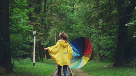 Vista-Trasera-De-Una-Mujer-Joven-Con-Un-Impermeable-Amarillo-Caminando-Con-Un-Paraguas