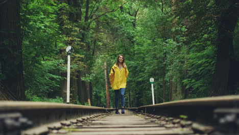 Girl-In-A-Yellow-Raincoat-Walking-On-The-Railway-And-Getting-Closer-To-The-Camera