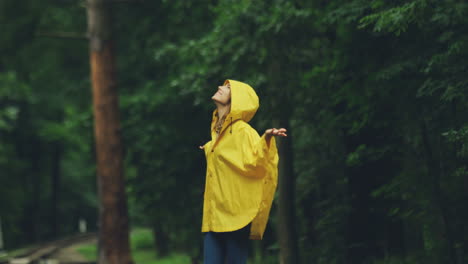 Attractive-Girl-In-A-Yellow-Raincoat-Raising-Her-Hands-Up
