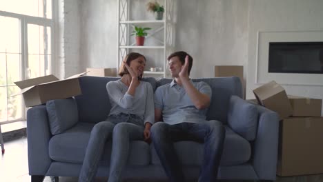 Young-Woman-And-Man-Rest-Satisfied-On-The-Sofa-After-Moving-To-Their-New-Home