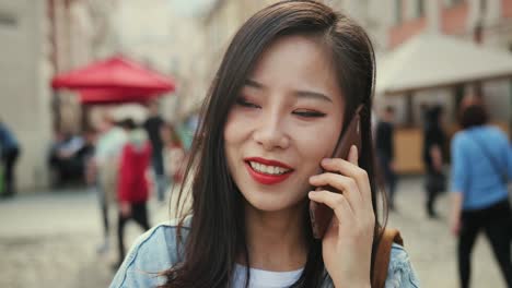 Close-Up-Of-The-Young-Pretty-Girl-Talking-On-The-Phone-While-Standing-In-The-Center-City-At-Daytime