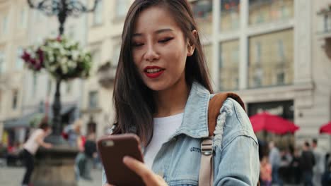 Close-Up-Of-The-Young-Pretty-Woman-Standing-At-The-Street-In-European-City-And-Having-Videochat-On-The-Smartphone-Cheerfully