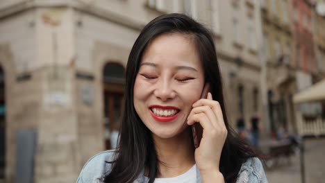 Close-Up-Of-The-Pretty-And-Happy-Young-Woman-Talking-On-The-Phone-And-Smiling-Joyfully-In-The-Historical-Center-City