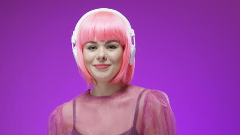 Portrait-Of-Beautiful-Woman-Wearing-A-Pink-Wig-And-Headphones,-Dancing-And-Laughing-To-The-Camera