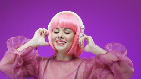 Portrait-Of-Beautiful-Woman-Wearing-A-Pink-Wig-And-Headphones,-Dancing-And-Laughing-To-The-Camera-1