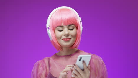 Beautiful-Woman-Wearing-A-Pink-Wig-And-Big-Headphones-With-Smartphone-In-Hands,-Dancing-And-Laughing