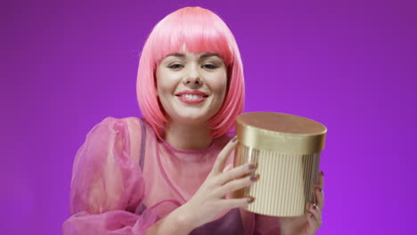 Beautiful-Woman-Wearing-A-Pink-Wig-Holding-Golden-Box-With-A-Present-And-Smiling