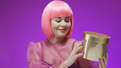 Beautiful-Woman-Wearing-A-Pink-Wig-Holding-Golden-Box-With-A-Present-And-Smiling-1