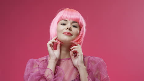 Portrait-Of-Beautiful-Woman-Wearing-A-Pink-Wig,-Dancing-And-Laughing-To-Camera-On-Bright-Pink-Wall-Background