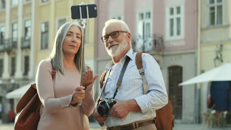 Pareja-De-Ancianos-Parados-Juntos-Con-Un-Teléfono-Inteligente-En-El-Selfie-Stick-Y-Haciendo-Un-Video-O-Teniendo-Videochat