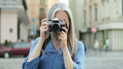 Portrait-Of-Senior-Woman-With-Long-Hair-Standing-In-Front-Of-The-Camera-And-Taking-Photos