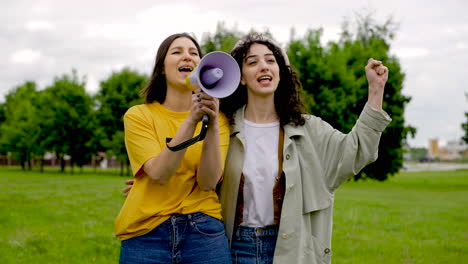 Two-Female-Friends-In-A-Protest-Using-A-Megaphone