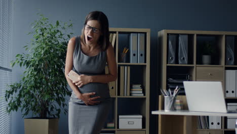 Schwangere-Frau,-Die-Im-Büro-An-Ihrem-Arbeitsplatz-Telefoniert-Und-Starke-Schmerzkrämpfe-Im-Bauch-Verspürt