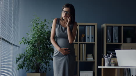 Mujer-Embarazada-Hablando-Por-Teléfono-En-La-Oficina-De-Su-Lugar-De-Trabajo-Y-Sintiendo-Fuertes-Espasmos-De-Dolor-En-El-Vientre-1