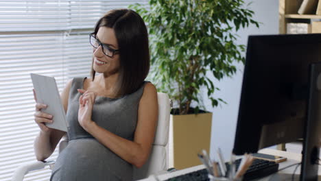 Schwangere-Geschäftsfrau-Mit-Brille,-Die-Im-Büro-Sitzt-Und-Den-Tablet-Bildschirm-Berührt-2