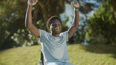 Glücklicher-Schwarzer-Kerl-Im-Rollstuhl,-Der-Die-Arme-Hebt-Und-Lacht