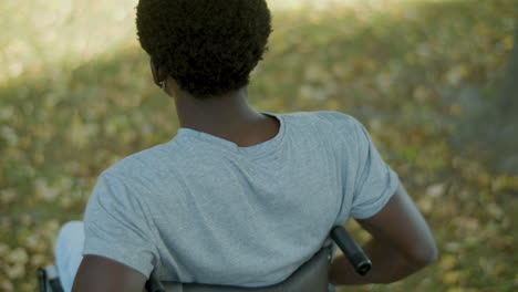 Back-View-Shot-Of-Black-Man-Riding-Wheelchair-Outside