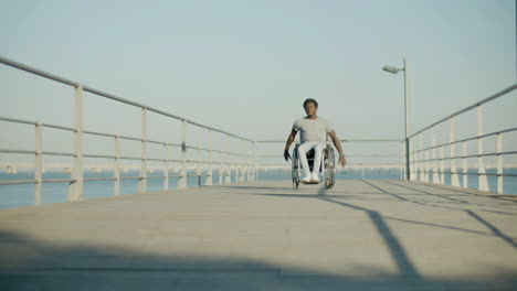 Front-View-Shot-Of-Black-Man-Riding-Wheelchair-At-Seafront