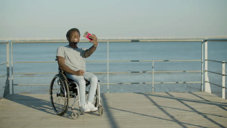 Black-Man-In-Wheelchair-Taking-Selfie-Against-Sea-Background