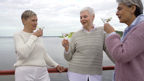 Three-Senior-Women-Having-A-Drink-Close-To-A-Lake-1