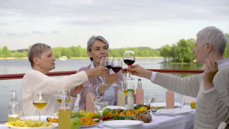Three-Senior-Women-Toasting-With-Wine-Glasses-Before-Having-Dinner