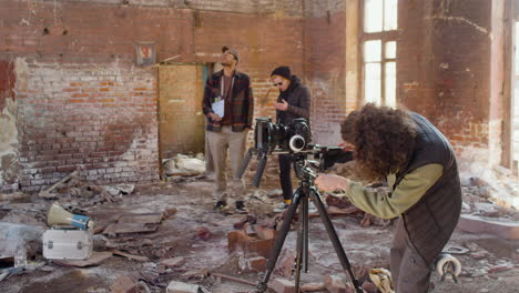 Production-Worker-Setting-Up-A-Camera-In-A-Ruined-Building