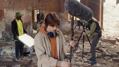 Woman-Production-Worker-Setting-Up-The-Microphone-And-The-Looks-At-The-Camera