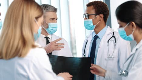 Ärzteteam-Diskutiert-über-Digitales-Tablet-Im-Korridor-Des-Krankenhauses