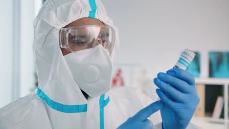 Cierre-De-Un-Trabajador-Médico-Especialista-En-Laboratorio-Con-Traje-Protector-Que-Llena-Una-Jeringa-Con-La-Vacuna-Contra-El-Coronavirus