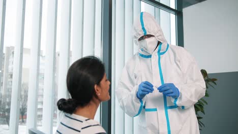 Portrait-Of-Healthcare-Worker-In-Protective-Suit-And-Gloves-Taking-From-Female-Young-Patient-Sample-For-Analysis-And-Coronavirus-Test-Working-In-Hospital-Laboratory,-Covid-Pandemic-Concept