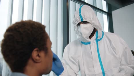 Close-Up-Of-Healthcare-Worker-In-Protective-Uniform-And-Medical-Mask-Taking-Saliva-Sample-For-Coronavirus-From-Male-Patient-For-Test,-Pcr-Testing-In-Hospital,-Covid-19-Virus