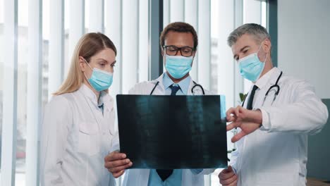 Portrait-Of-Team-Of-Medical-Workers-Female-And-Male-Doctors-In-Medical-Mask-Standing-In-Hospital-Speaking-Discussing-X-Ray-Scan,-Patient-Analysis-Results-And-Treatment,-Healthcare,-Pandemic-Concept